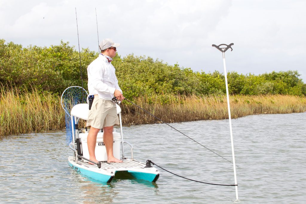 Photo of guy anchored on stand up paddle board fishing