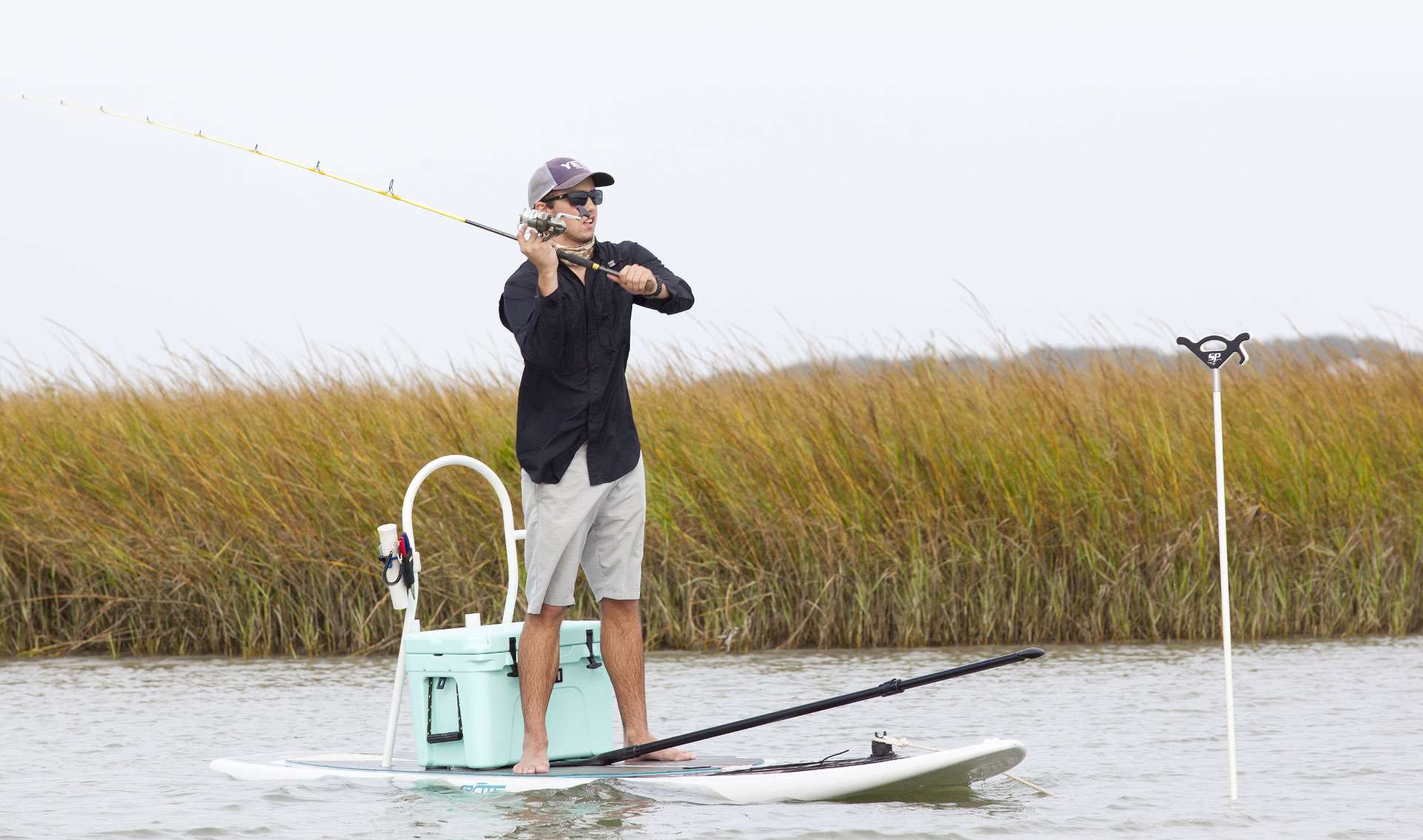Photo of guy fishing on stand up paddle board anchored up with Stayput pole anchor